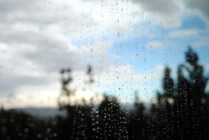 Photo of a blue sky through a rain-spattered window