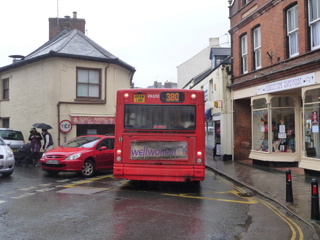 A bus to the right of a red car.