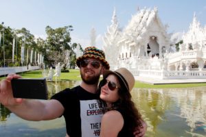 Two people taking a selfie in front of a white temple
