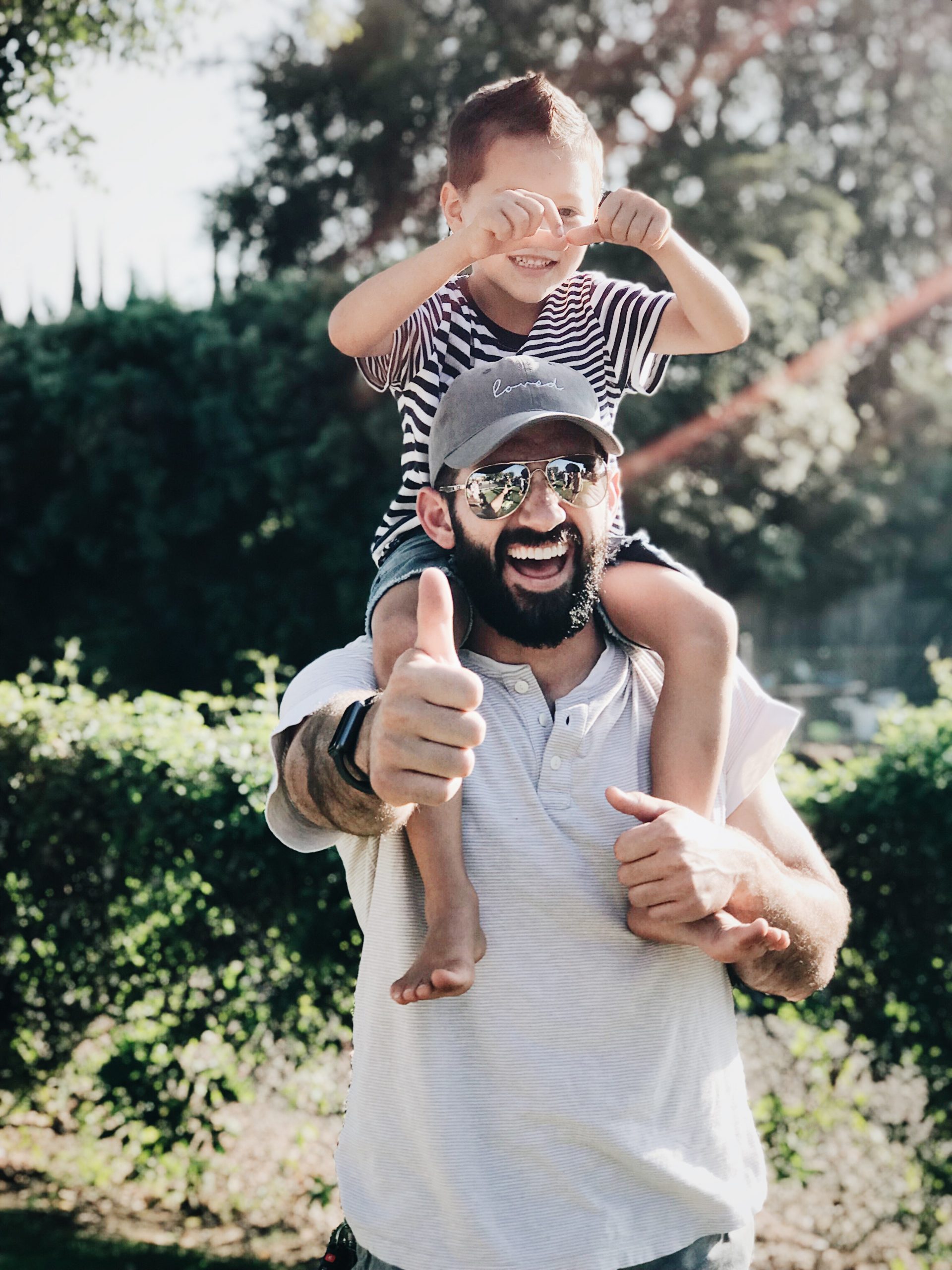man holding his son and giving thumbs up