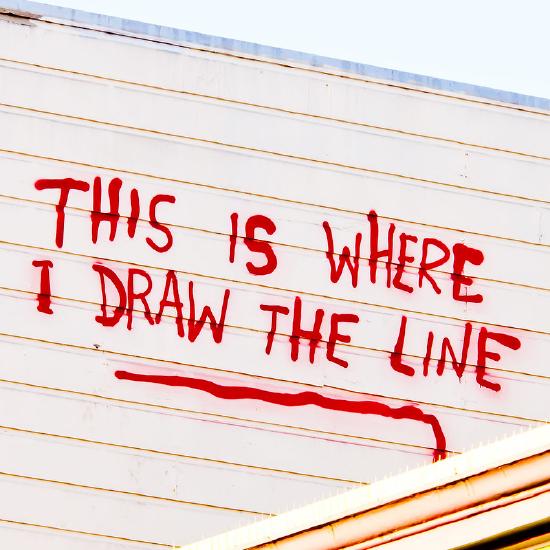 "This is where I draw the line" scrawled in red on the side of a building.