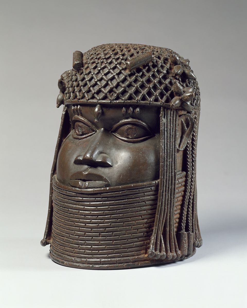 A Benin cast bronze head with long hair and a woven hat with several necklaces around her neck
