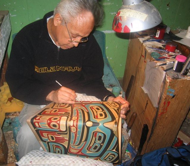 'Namgis master carver Bruce Alfred painting a bentwood box
