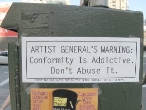 Sign in urban landscape saying Conformity is Addictive; don't abuse it.