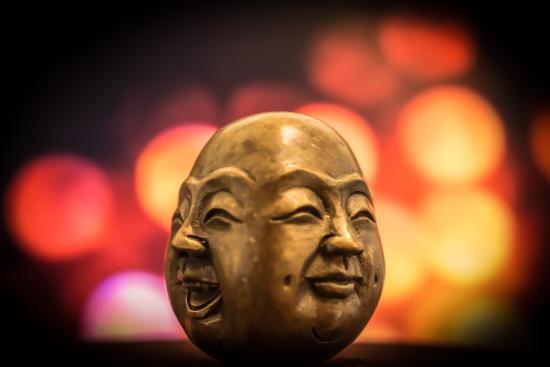 An image of two faces of the Buddha blended together, one laughing and one smiling peacefully.