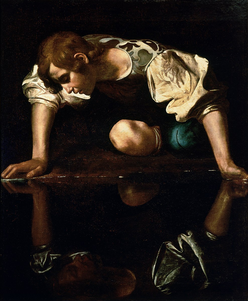 A man sitting on the ground staring at his own reflection