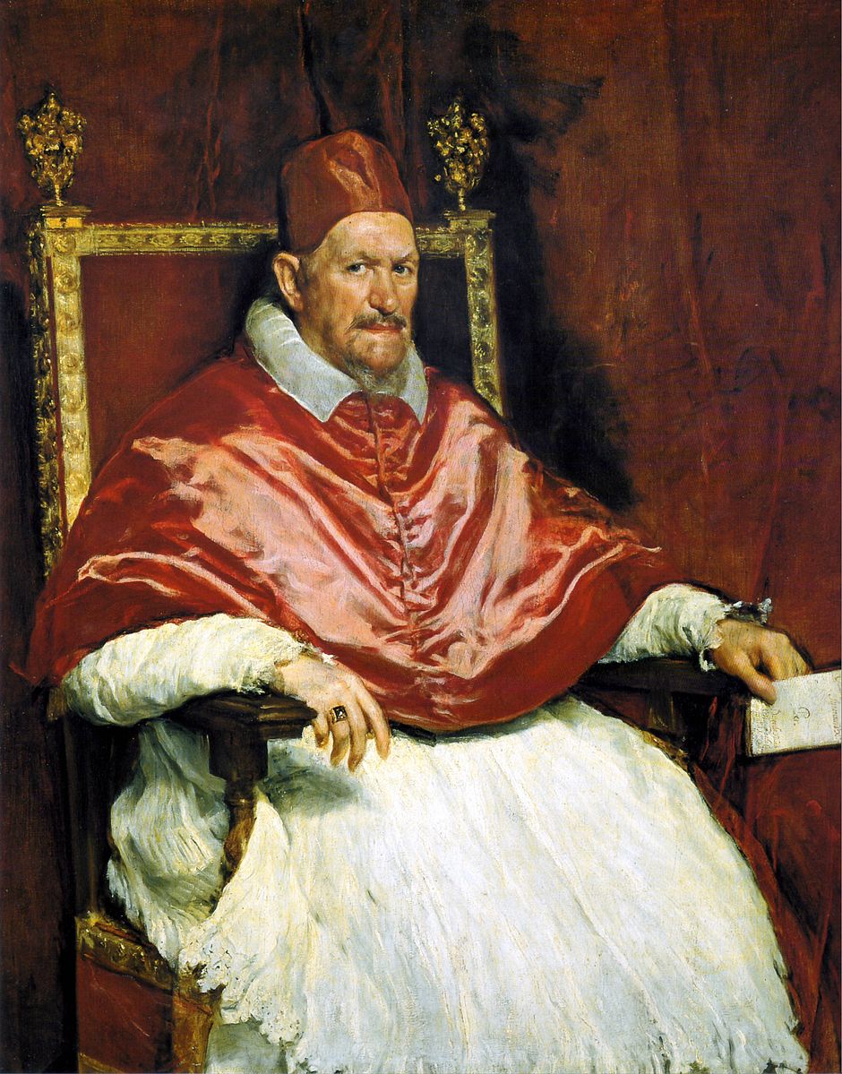 Pope sitting in a gold chair with a red robe and white gown