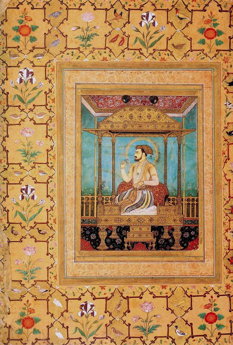 A nan sitting on an ornate rug under a temple piece