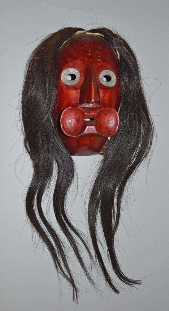 A mask with a red face and long black hair and white eyes