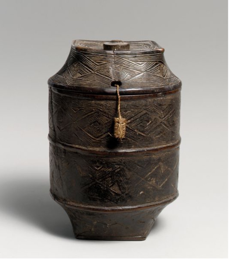 a large wooden vessel with ornate carving around and a lid