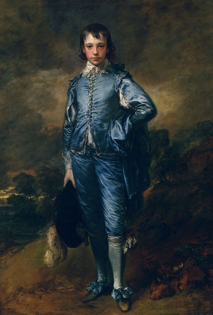 A boy dressed in blue silk standing against a dark background
