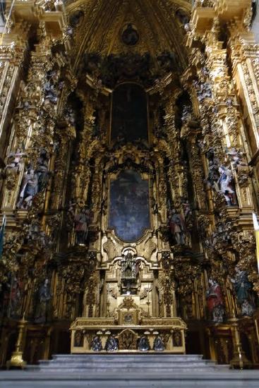 Ornate religious church altar in gold and several paintings