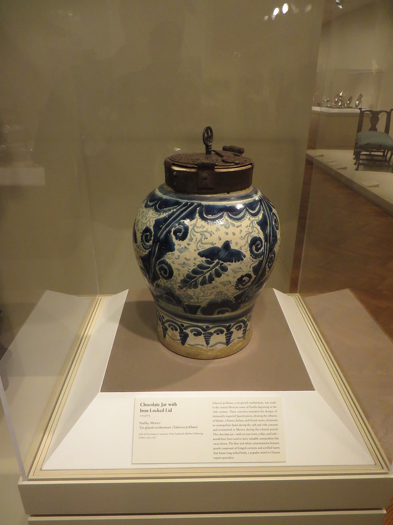 A white and blue vase with a brown lid