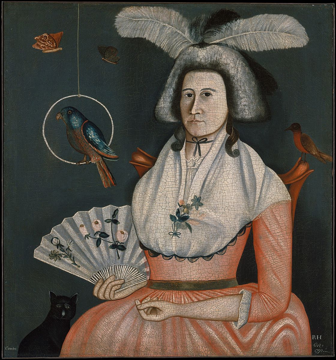 Lady sitting in a chair with a pink dress and two feathers in a hat holding her pets