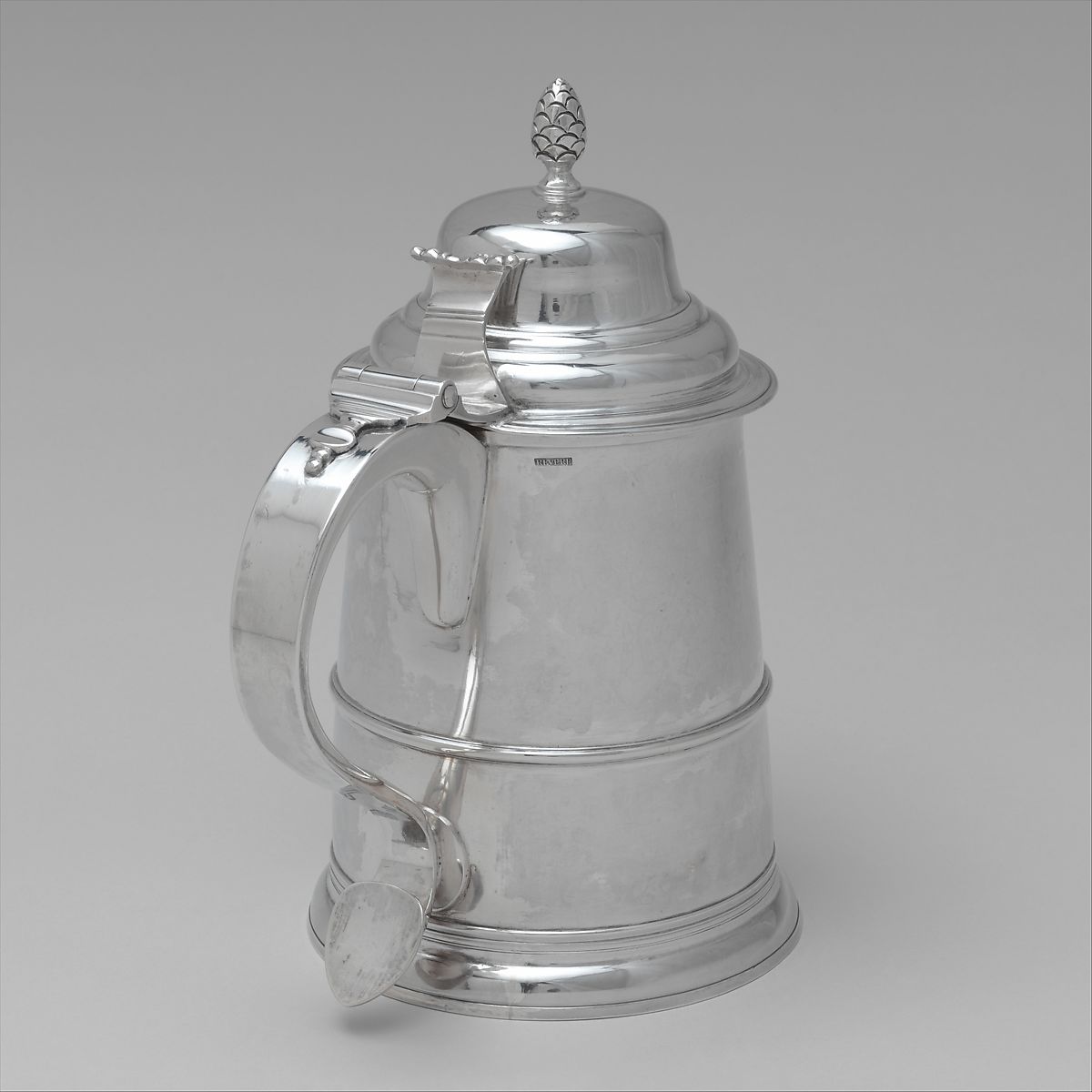 A silver tankard with a handle and a lid