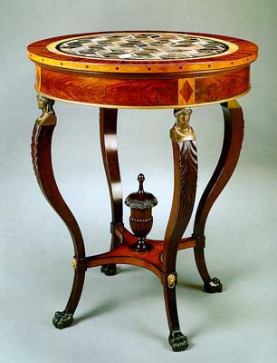 A circular table with 4 legs with an inlaid top