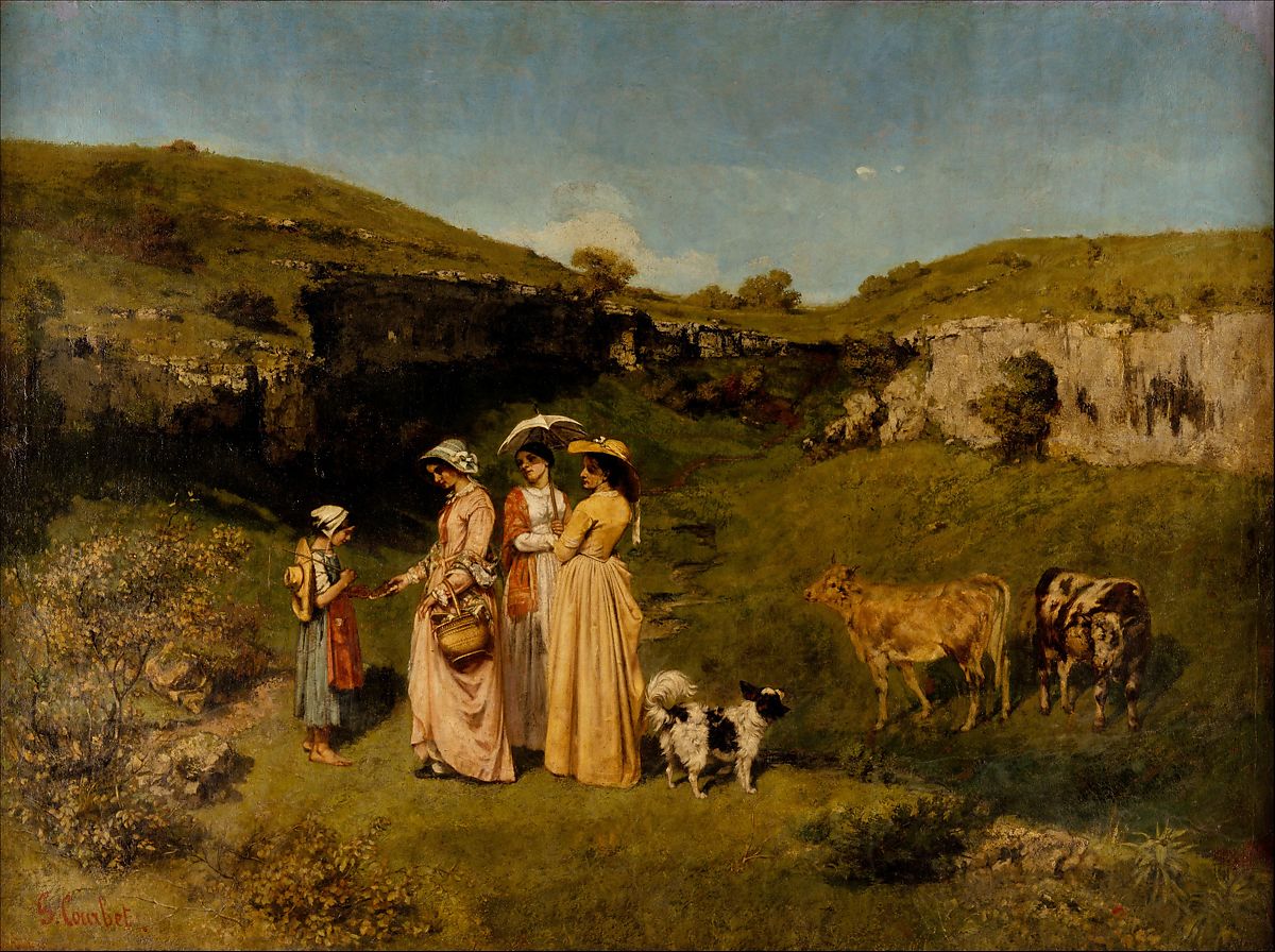 Four people standing in a field surrounded by hills of green grass and two cows