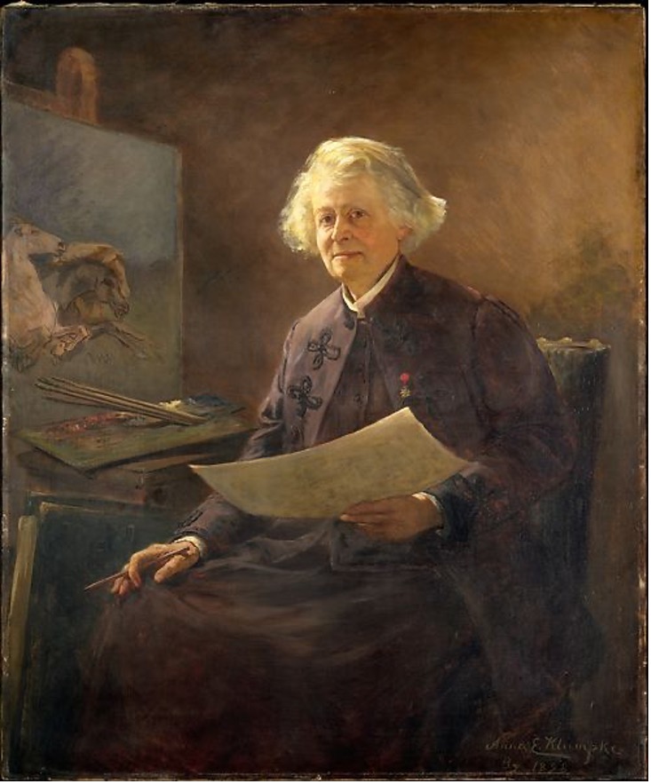 Una mujer artista vistiendo un traje morado oscuro pintando en un caballete