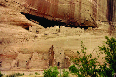 Uma fotografia das habitações do penhasco de Anasazi mostra estruturas de adobe em blocos com aberturas de janelas e portas, algumas das quais estão situadas no topo de um penhasco alto e íngreme.