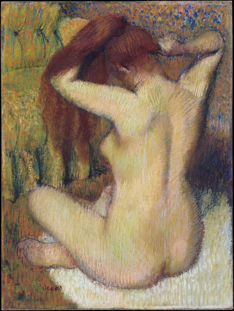 A nude woman sitting on a towel taking a bath putting her long orange hair up