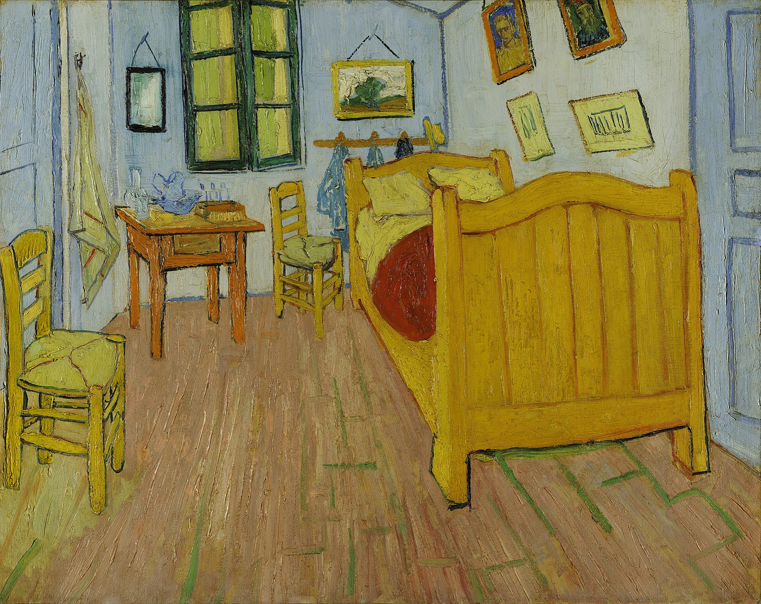 A bedroom with a wooden floor, yellow bed and chair with paintings on the wall