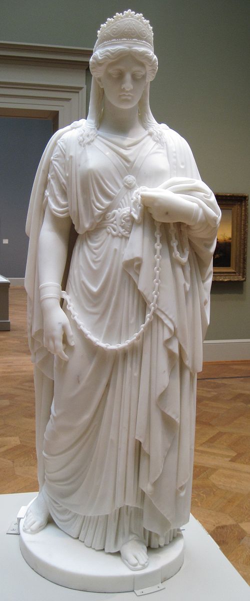 A woman carved in marble with a dress and her arms chained together