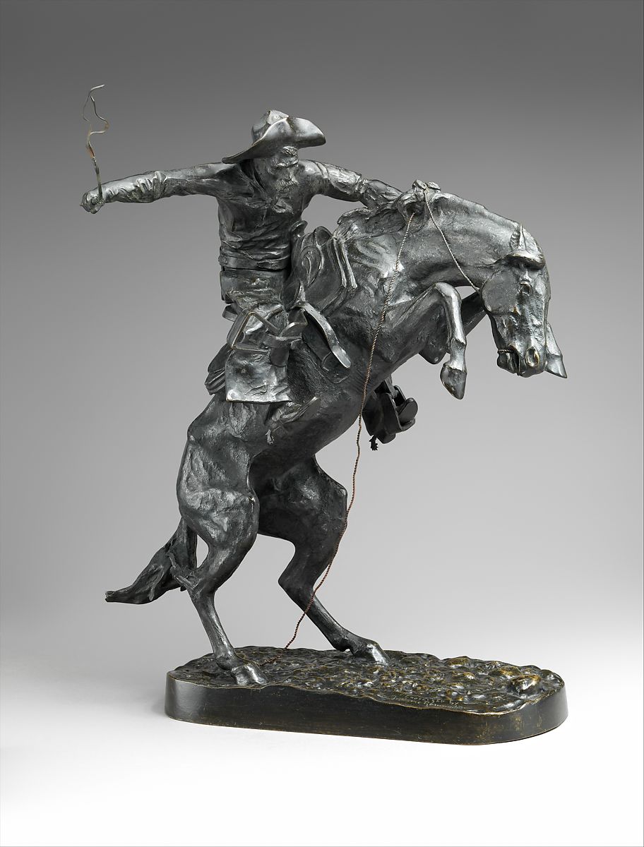 A bronze statue of a man riding a horse that is bucking up