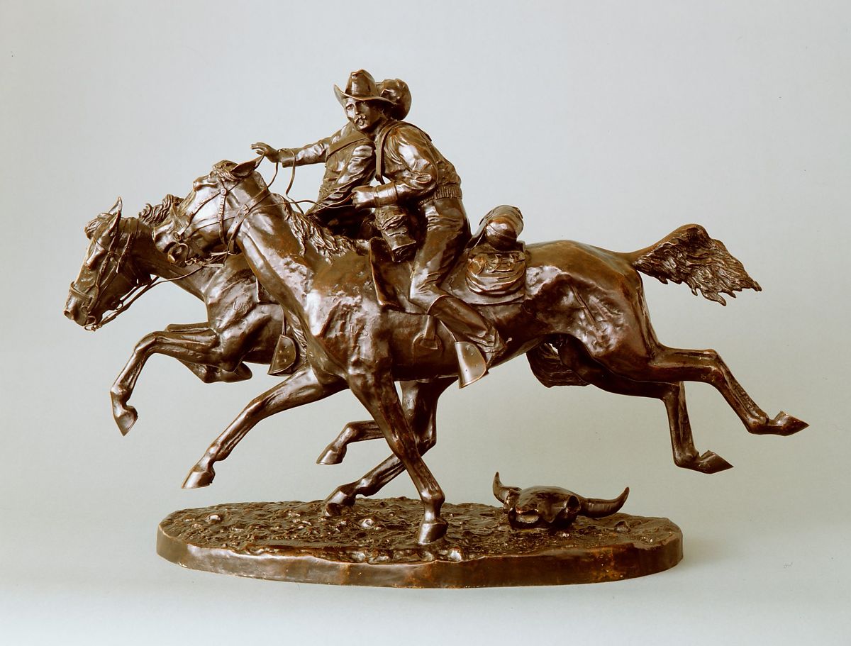 A bronze statue of two men on two horse in a fast gallop
