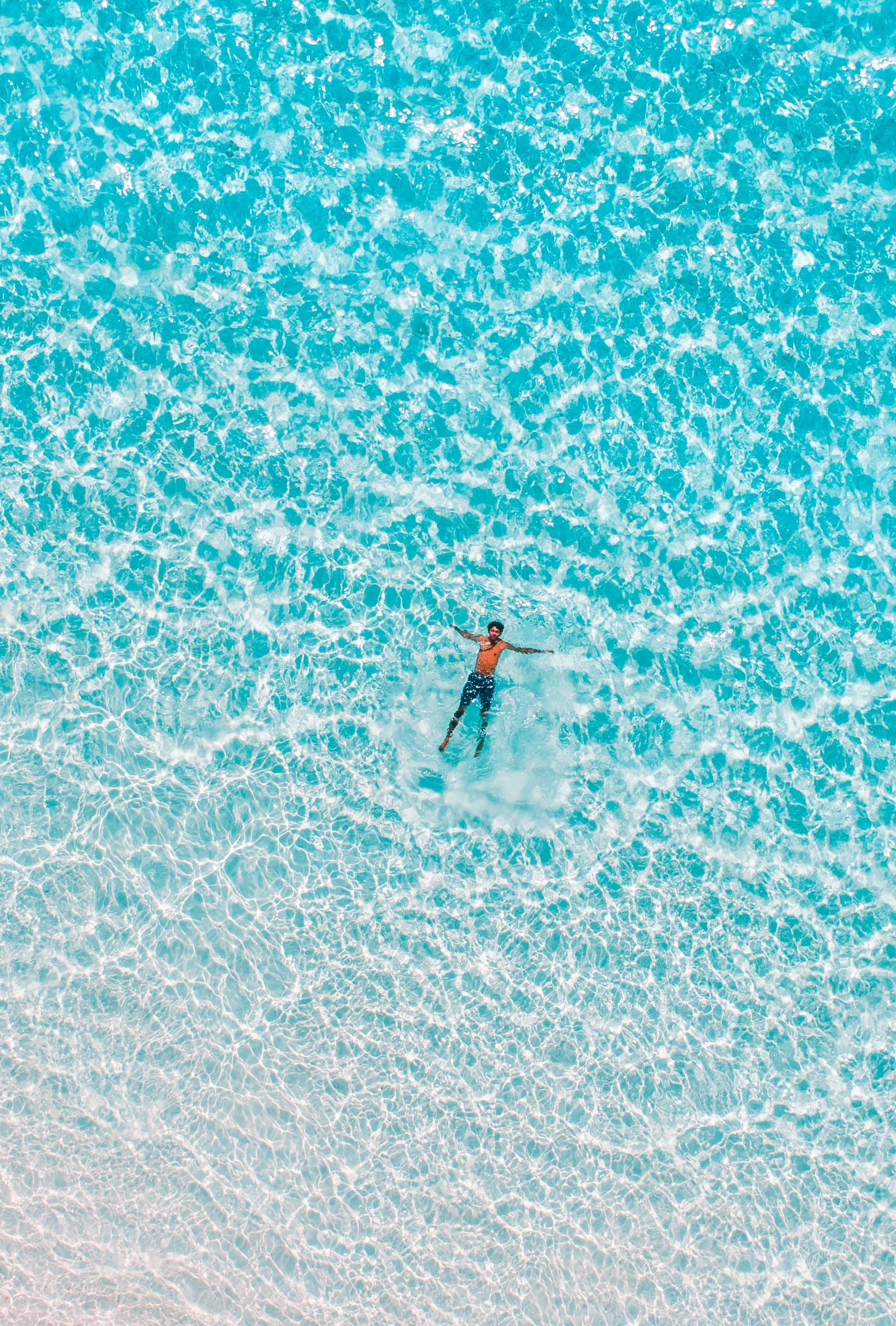 Une petite figure d'une personne entièrement habillée flottant dans un océan tranquille.