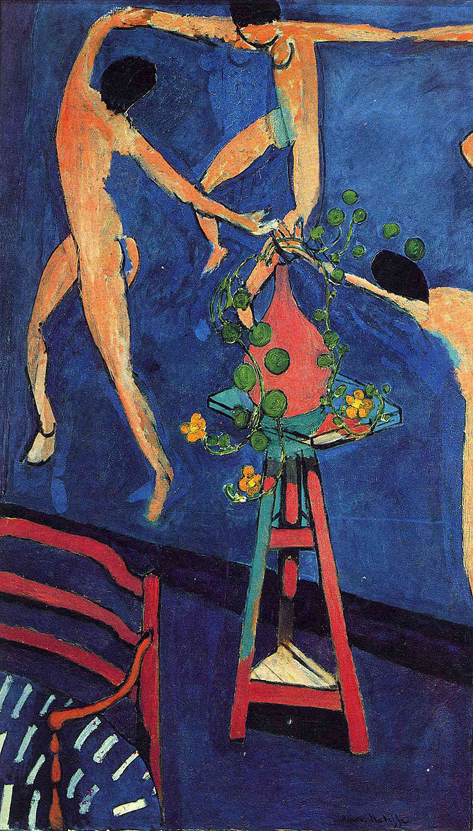 Three nude woman holding hands in a circle dancing on a blue surface with a red chair in the front