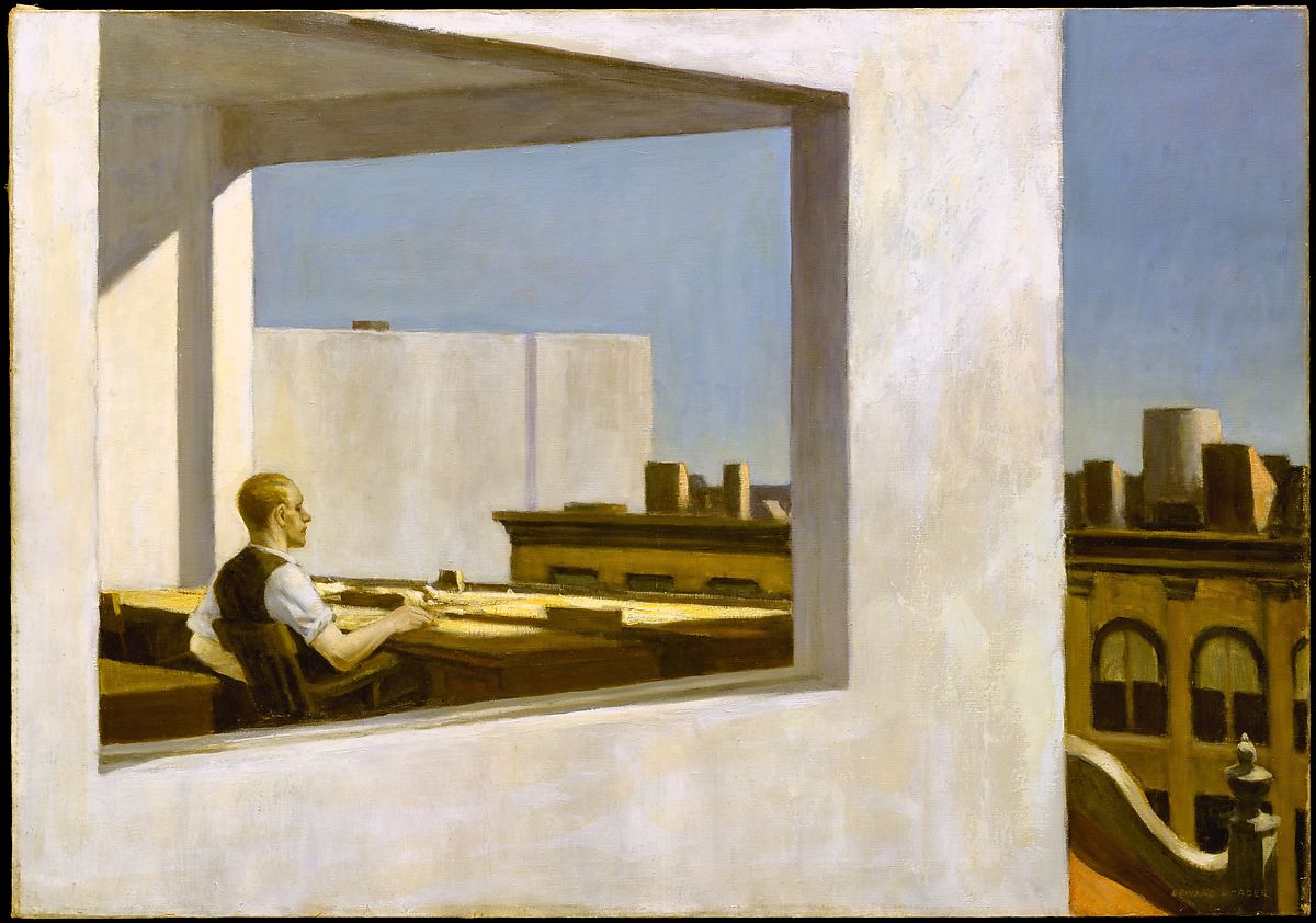 Man sitting at a desk looking out the large window at a city scape