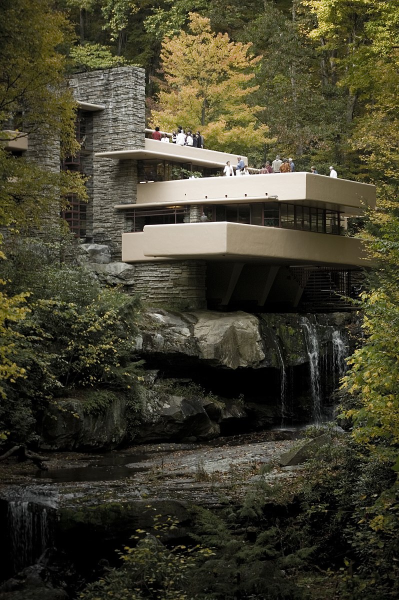 Three story house built from concrete and stone positioned over a large waterfall