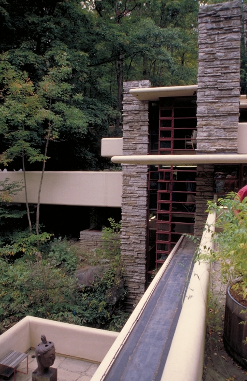A stone and concrete house with multiple windows and decks