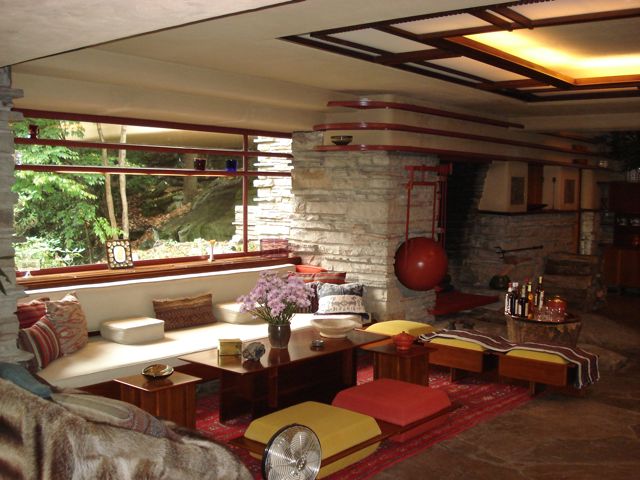 Inside of stone house with large windows and colorful couches in a sitting room