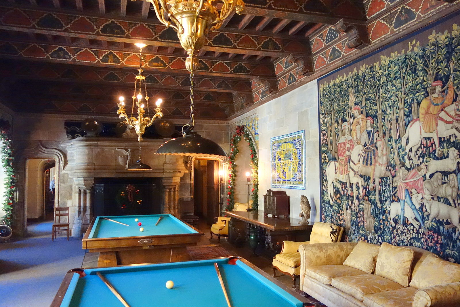 Una habitación adornada con dos mesas de billar y gran tapiz