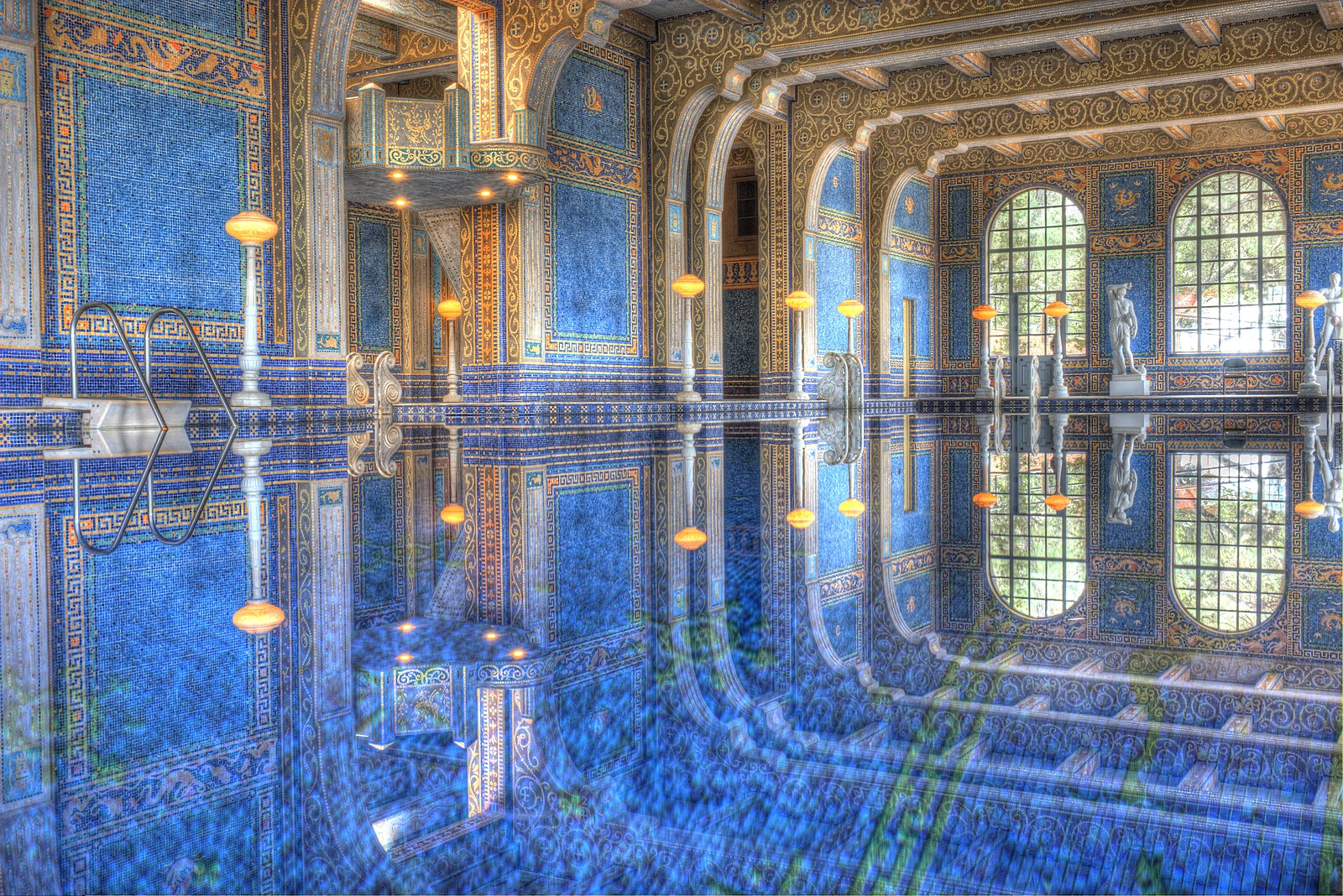 An indoor pool with blue and gold tile in ornate decorations