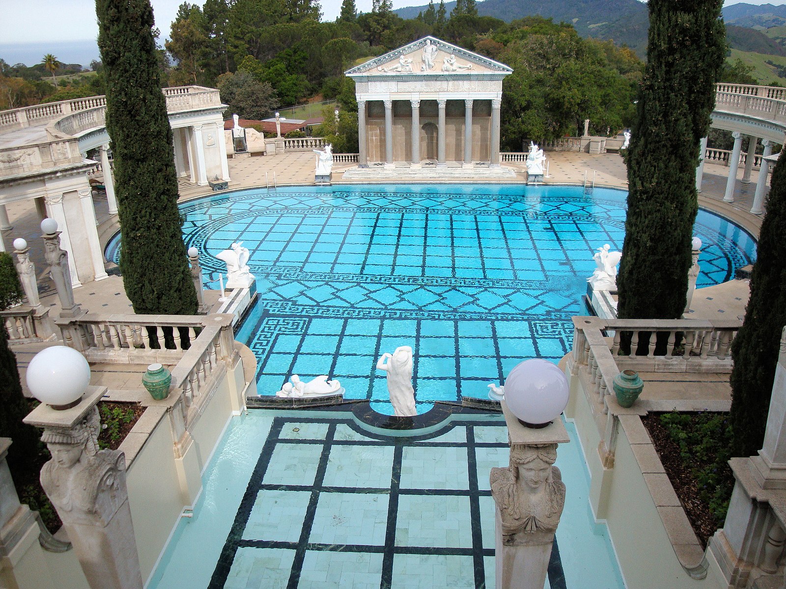 Outside pool with a grid of black lines on the bottom and ornate Roman sculptures