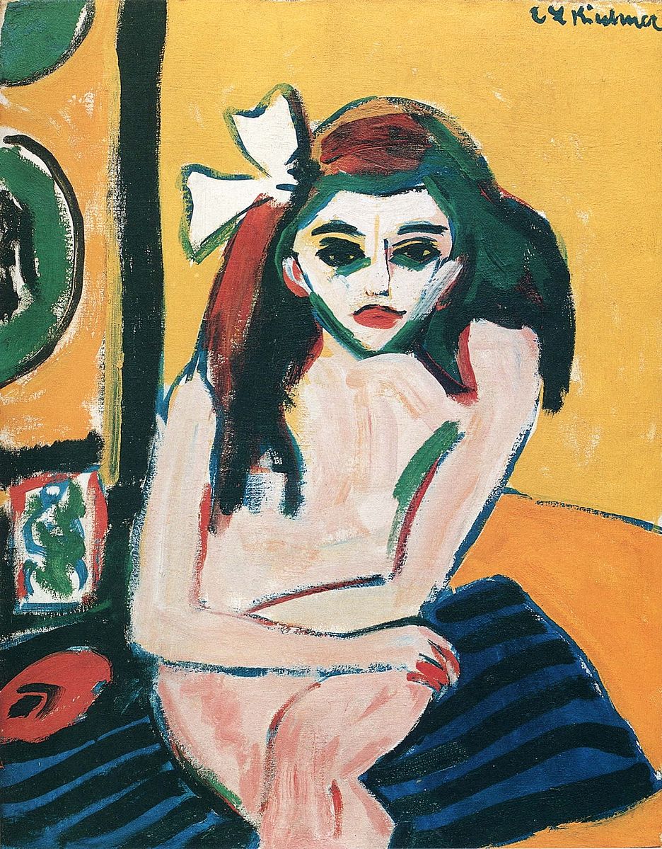 Young girl sitting on a green striped towel in a yellow room