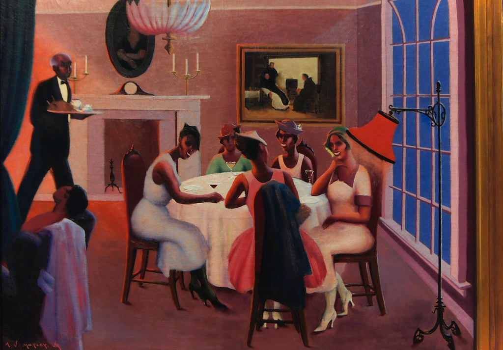 A waiter serving several women at a table inside a house