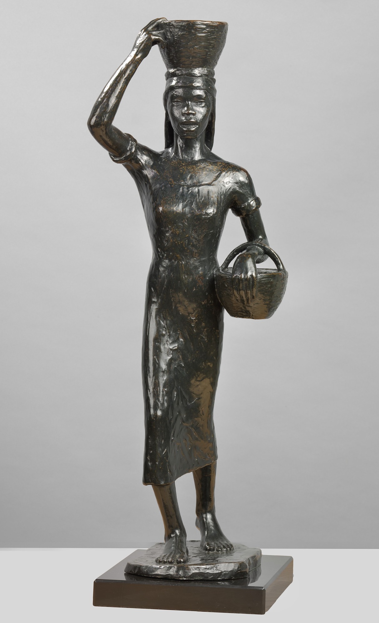 A bronze statue of a woman carrying a basket and another one on her head