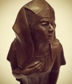A bronze statue of a woman waring a cloth on her head 