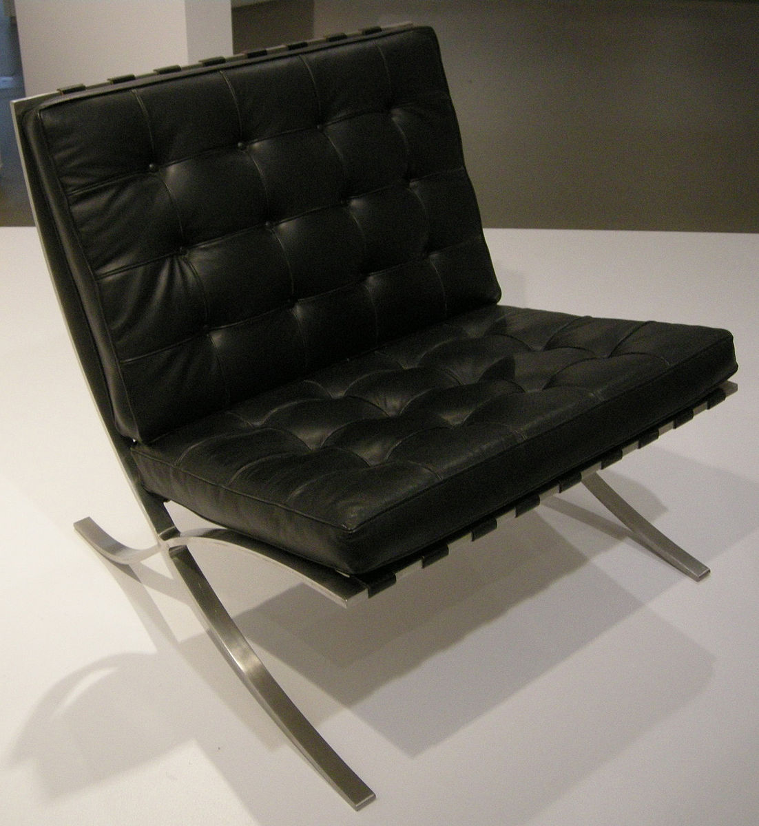 A black leather tufted chair with silver legs