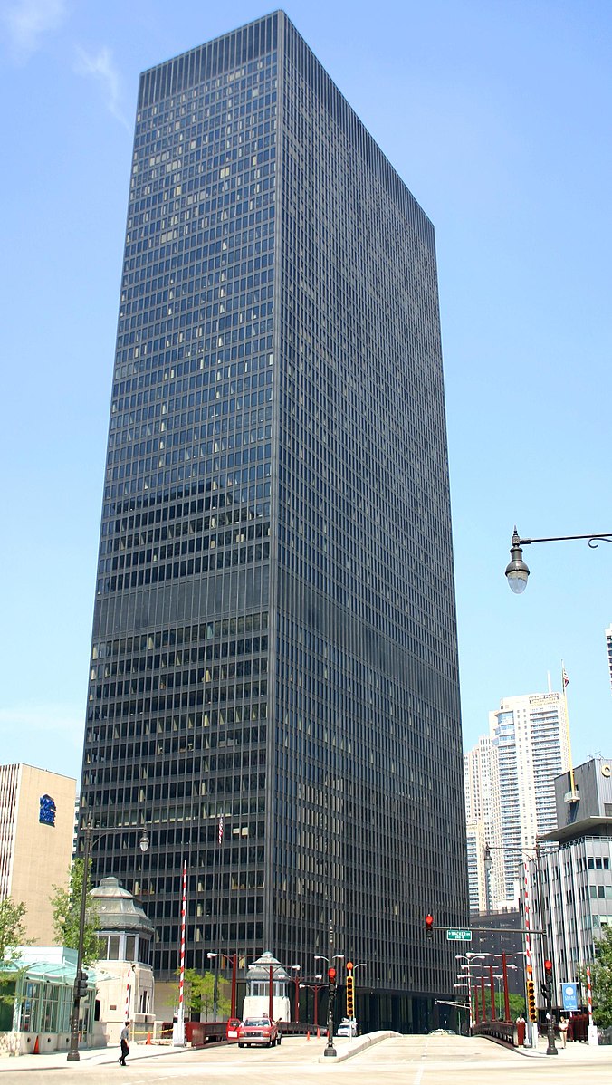 A tall building that is black with many windows on every side