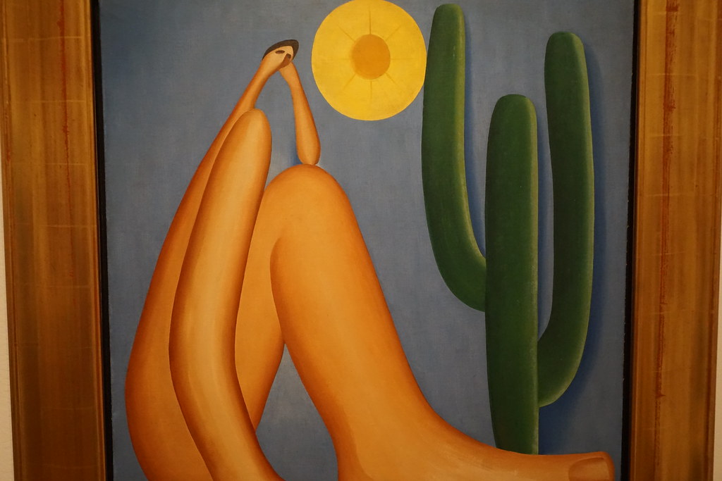 A nude woman with exaggerated legs and arms sitting by a cactus