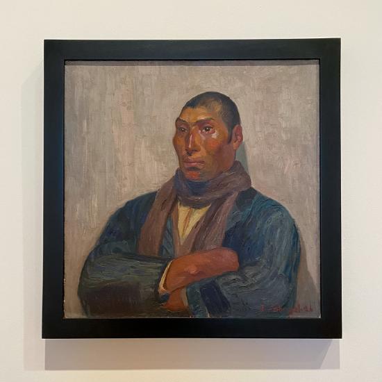 A portrait of a man against a white background wearing a blue jacket and marroon scarf