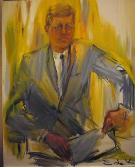 a man in a blue suit sitting at a desk reading a book