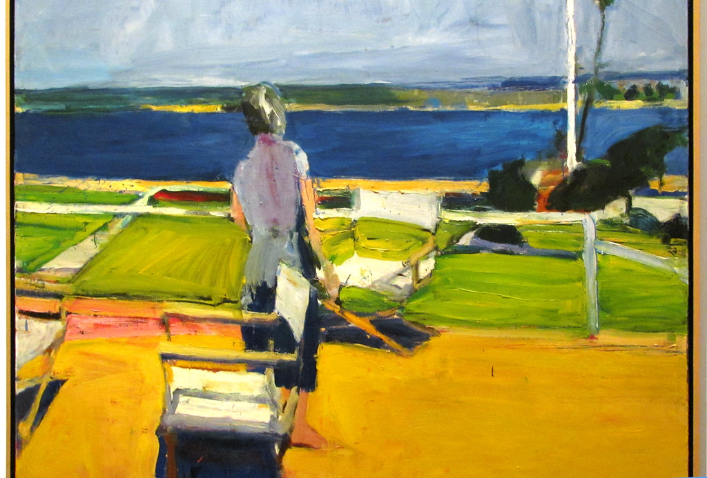 A women standing gazing upon a lake painted in multiple colors