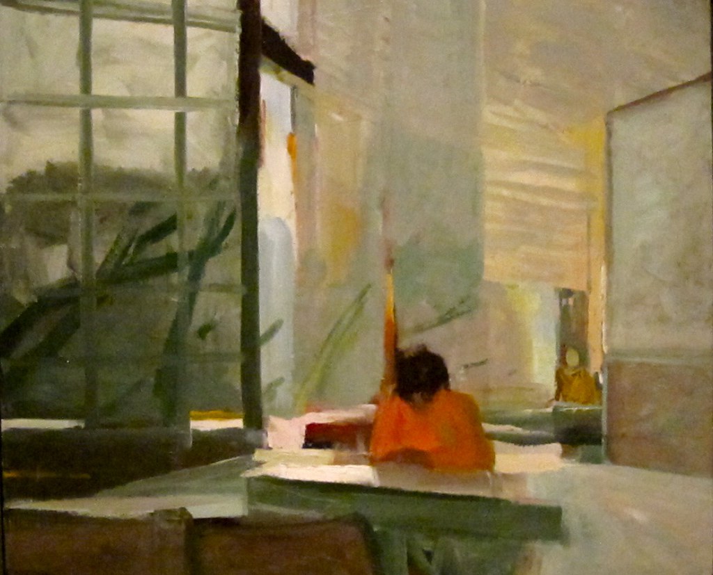 A woman sitting at a desk inside painted in multiple colors