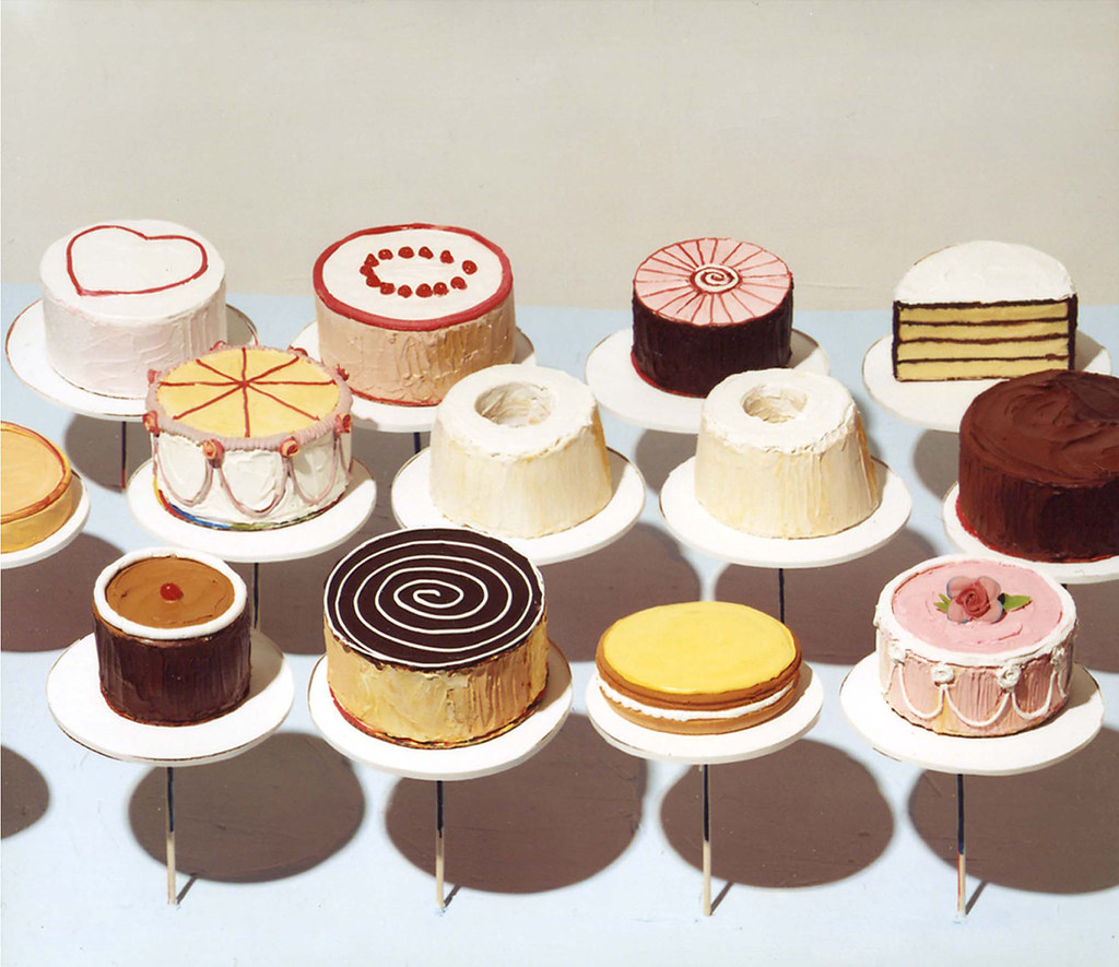 Several cakes on cake plates on display