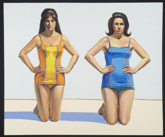 Two women in yellow and blue bathing suits on a beach